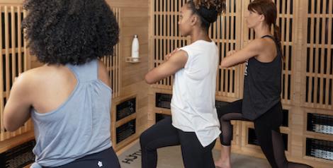 Three women stretching watching a virtual workout.