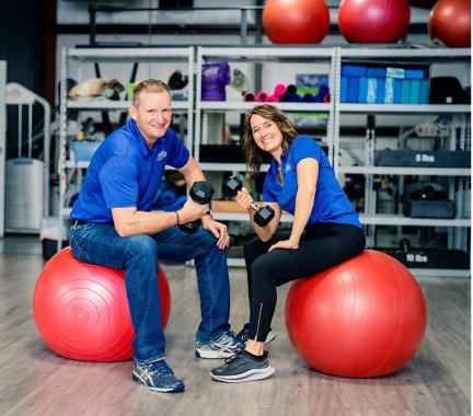 Two people sitting on rubber balls with weights: Groll Family Fitness