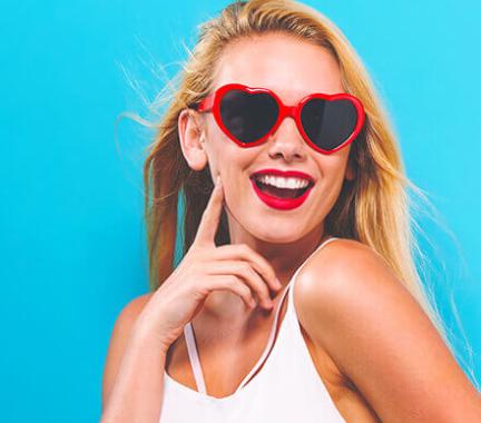 blue background with woman wearing heart shaped sunglasses