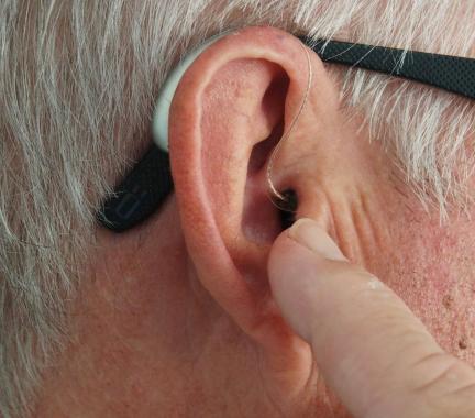 a grey haired man with a small hearing aid in his ear. 