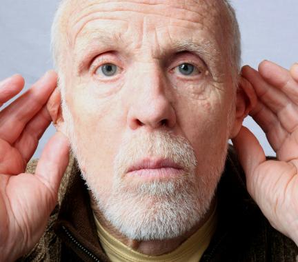 An older man with his hands cupped around each ear.