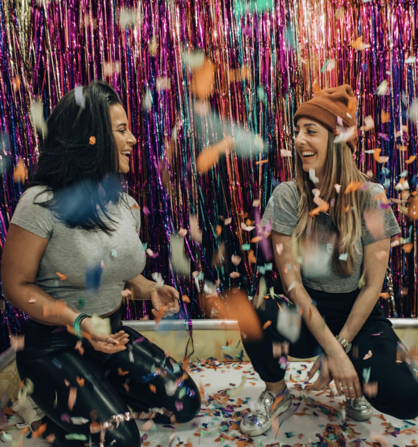 two girls sitting on their knees with streamers and confetti