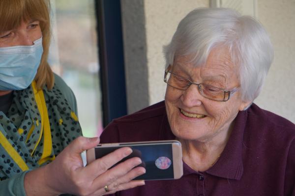 woman holding a phone for older woman to look at