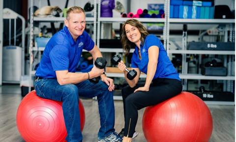 Two people sitting on rubber balls with weights: Groll Family Fitness