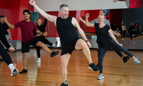 group fitness class with enthusiastic male instructor