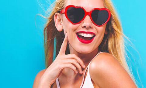 blue background with woman wearing heart shaped sunglasses