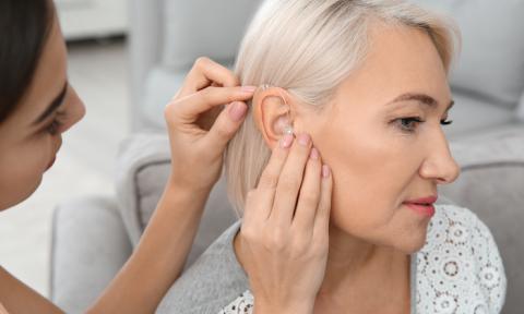 Woman fitting another woman for a hearing aid