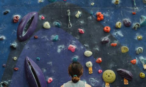 woman looking up at a rock climbing wall