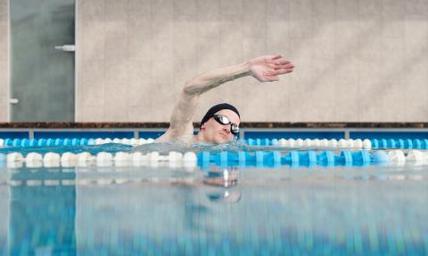 Man with swim cap and goggles swimming in a pool