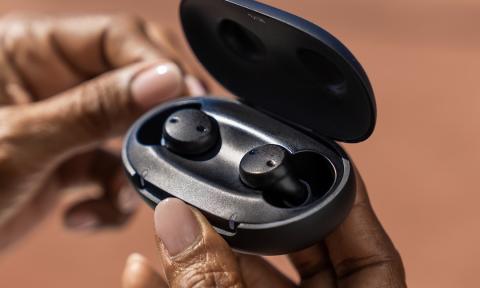 Black hearing aids in an opened handheld carrying case. 