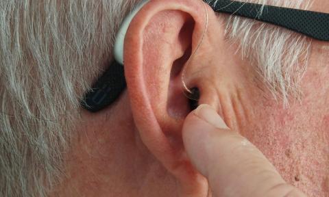 a grey haired man with a small hearing aid in his ear. 