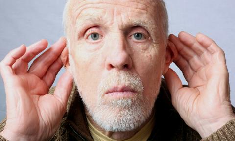 An older man with his hands cupped around each ear.