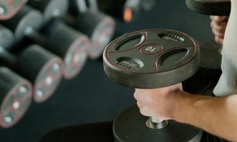 Man sitting on bench with a pair of dumbells in hands