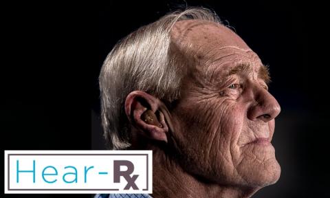 Side profile of elderly man with grey hair wearing a hearing aid with hear-rx logo in bottom left corner