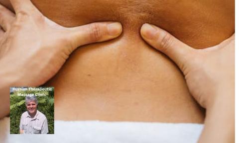 hands massaging a lower back with a white towel on the waist, photo of Sergio Vio massage therapist in bottom left corner