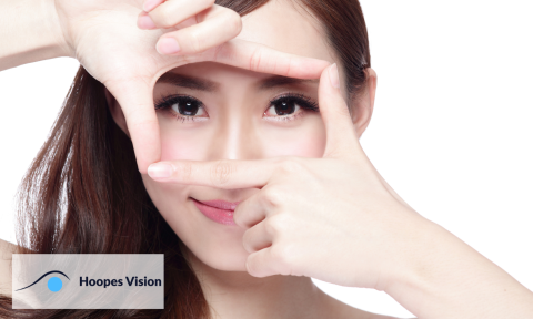 Woman smiling and hands up to her face framing her eyes with hoopes vision logo in bottom left corner