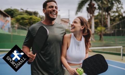 man and woman on pickleball courts laughing together with Sports Mall logo in bottom left corner