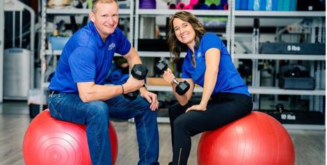 Two people sitting on rubber balls with weights: Groll Family Fitness