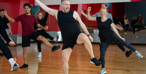 group fitness class with enthusiastic male instructor