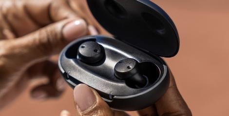 Black hearing aids in an opened handheld carrying case. 