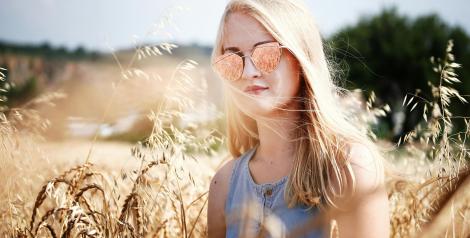 girl with long blonde hair wearing sunglasses in a wheat field