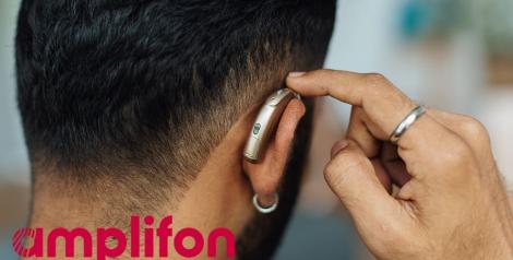 back of man's head with hearing aid and red amplifon logo in bottom left corner