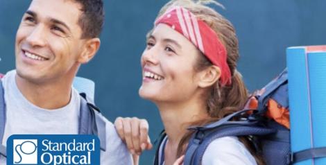 Man and woman with backpacking gear looking into the distance with Standard Optical logo in bottom left corner