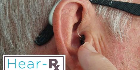 a grey haired man with a small hearing aid in his ear, Hear-RX logo in the bottom left corner