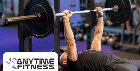 man bench pressing weights with anytime fitness logo in bottom left corner