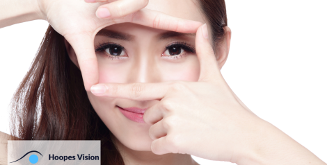 Woman smiling and hands up to her face framing her eyes with hoopes vision logo in bottom left corner