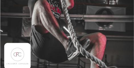 man climbing a rope in a dark gym, Crossfit Composure logo in bottom left corner