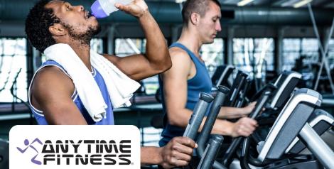 man with beard and dark hair drinking from a water bottle, on a treadmill, Anytime Fitness Logo on the bottom left corner