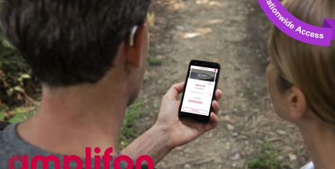 a man and woman on a hiking trail looking at a phone, man is wearing a small, silver hearing aid with amplifon logo in bottom left corner, purple banner top right corner reading nationwide access