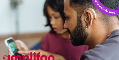 father with hearing aid reading on cell phone screen while daughter sits nearby, with amplifon logo in bottom left corner, purple banner top right corner reading Nationwide access