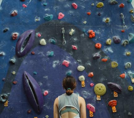 woman looking up at a rock climbing wall