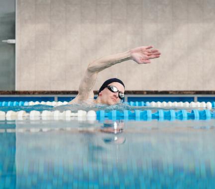 Man with swim cap and goggles swimming in a pool