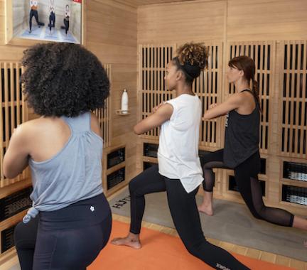 Three women stretching watching a virtual workout.