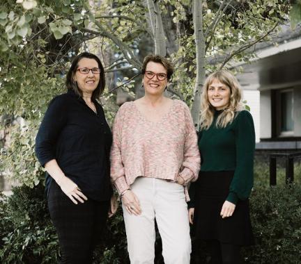 3 women standing in front of a tree