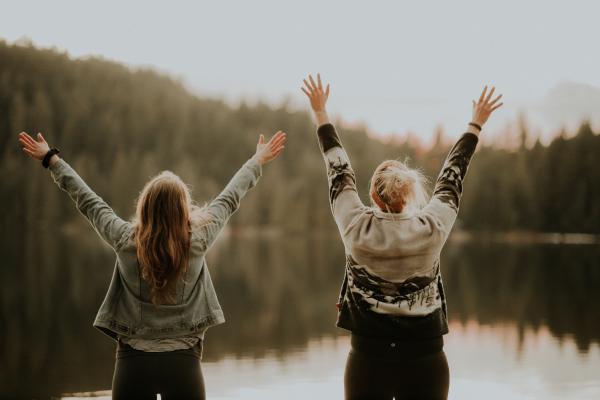 two women raising their arms in happiness